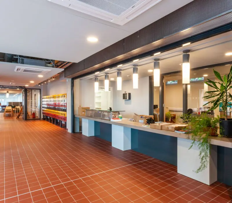 Modern interior with terracotta floor, long counter, hanging lights, and plants; bright and spacious hallway.