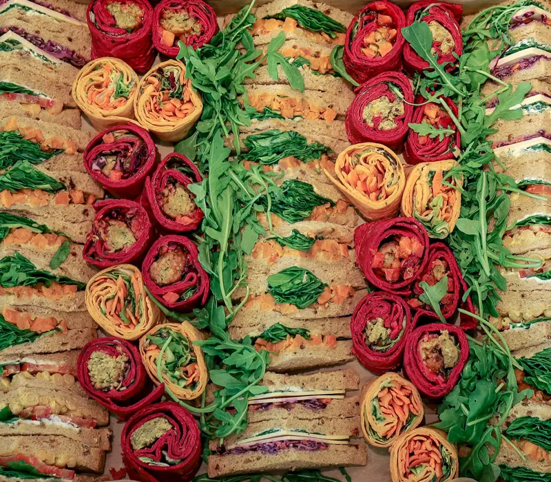 Assorted wraps and sandwiches with vibrant fillings, garnished with fresh arugula leaves for presentation.