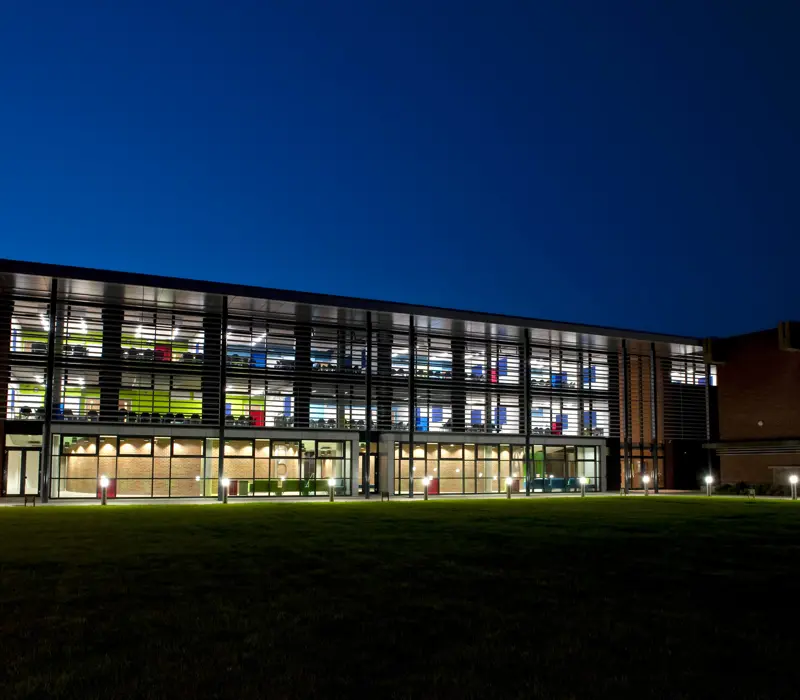 Modern building with large glass windows lit from within, against a clear night sky.